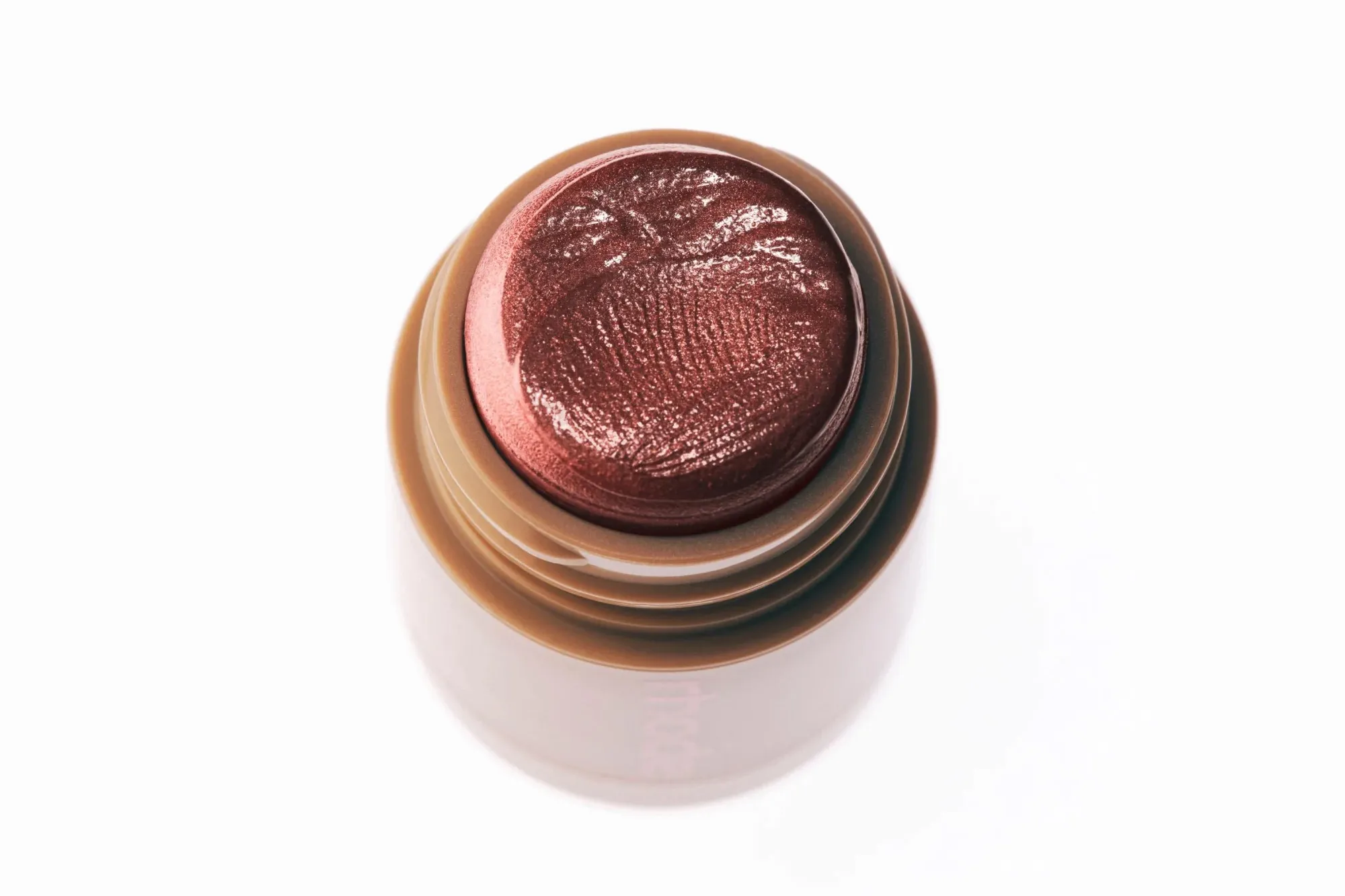 Close-up of a brown cream makeup stick on a white background.