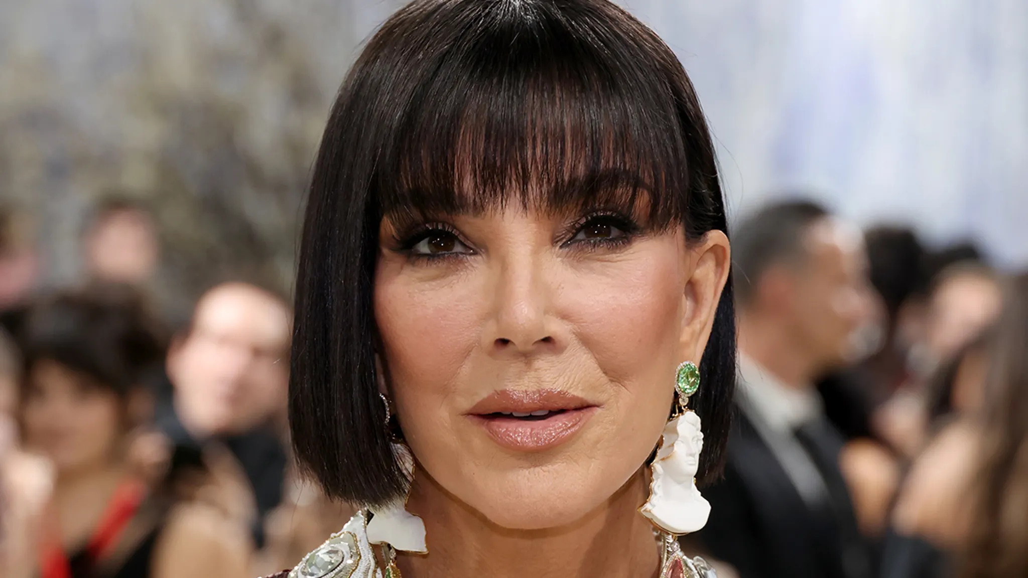Kris Jenner posing on a red carpet in a black outfit
