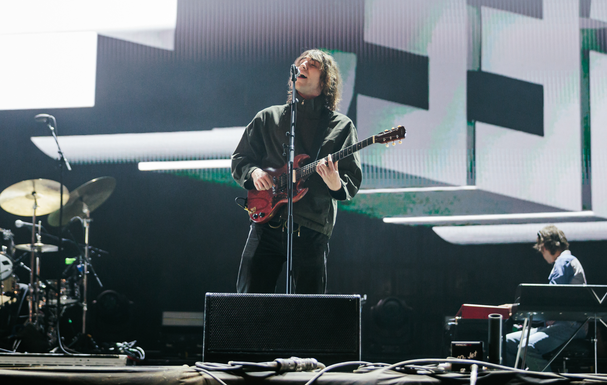 Geese frontman Cameron Winter performing on stage surrounded by lights