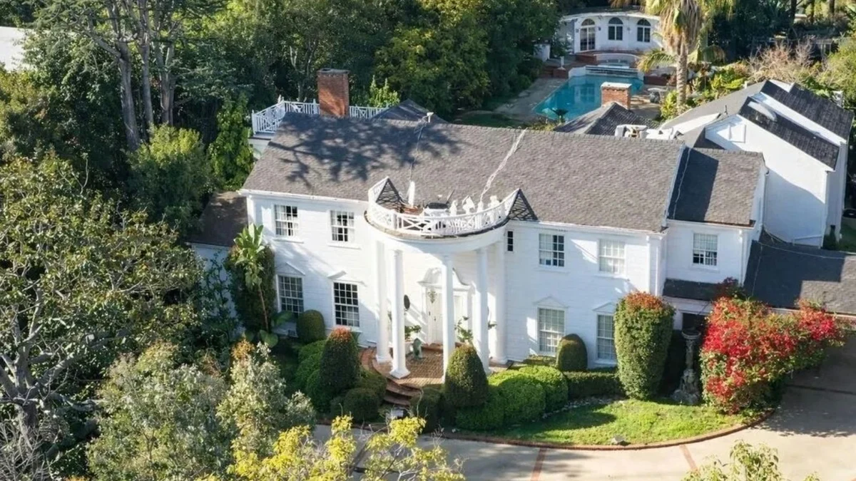Aerial view of white mansion with tress around