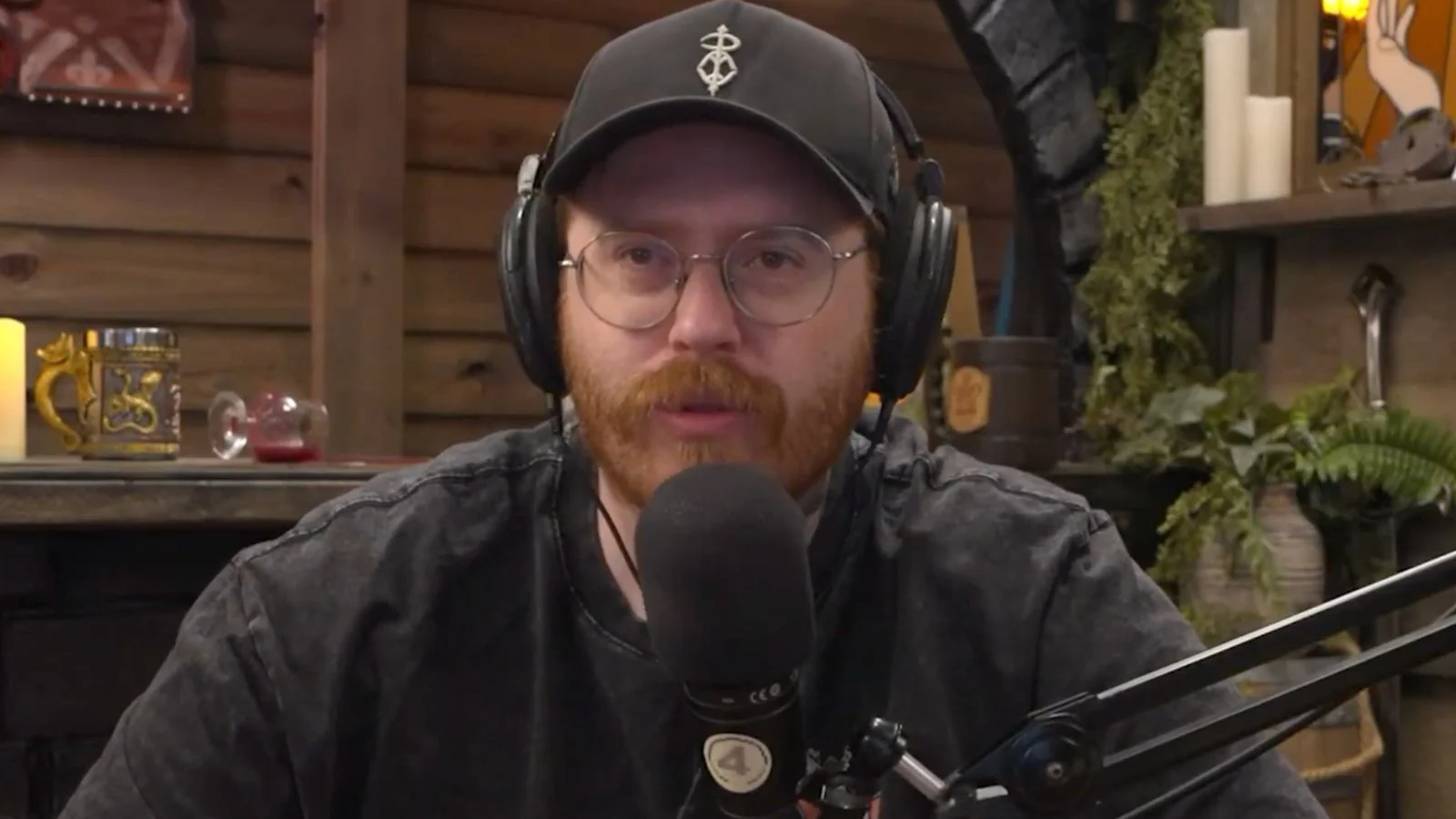 Man in black t shirt and hat talking into microphone