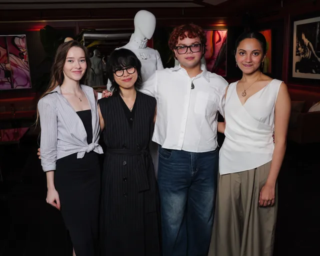 Image may contain People Person Clothing Pants Adult Blouse Accessories Glasses Jewelry Necklace and Photobombing