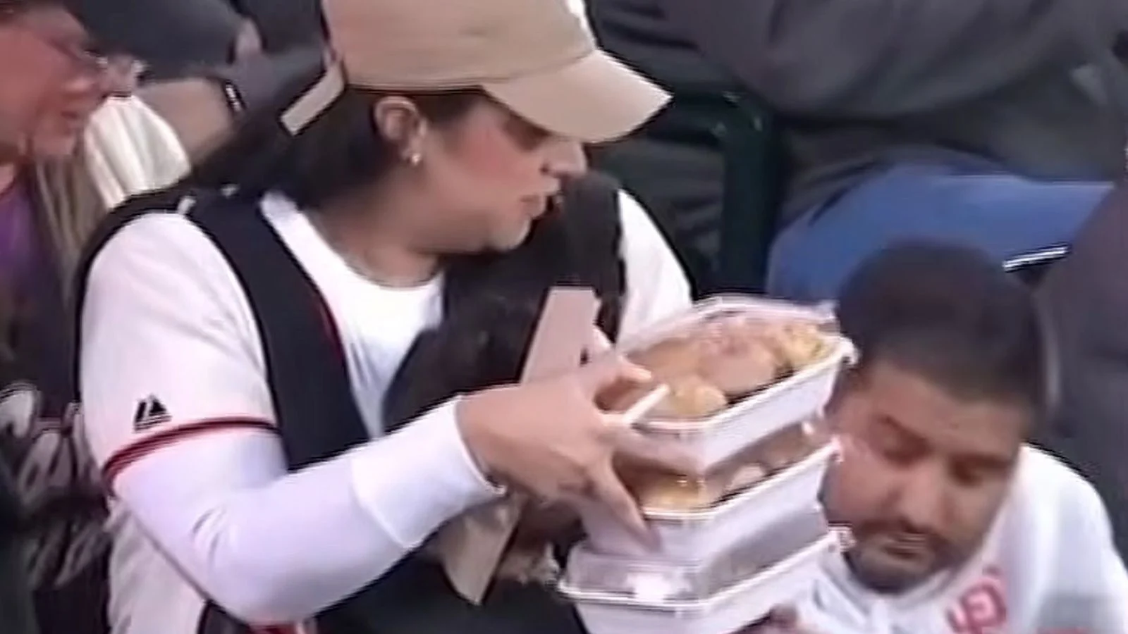 Woman in hat holding trays of food with man sat next to her