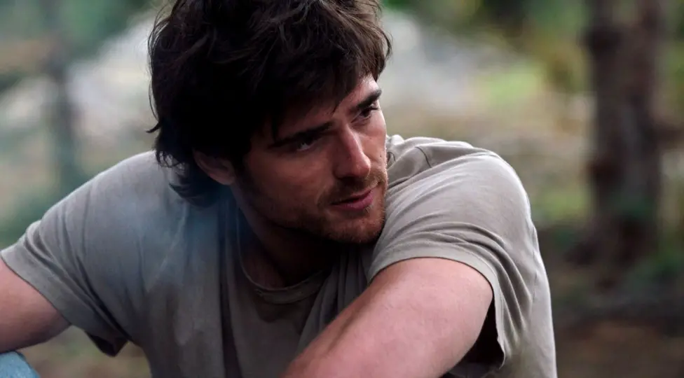 Jacob Elordi appears dishevelled with shaggy hair, a beard and wearing a light green t-shirt.