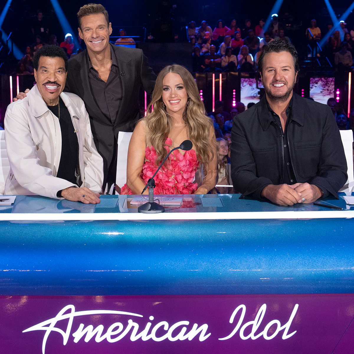 The American Idol logo displayed on a bright television studio stage
