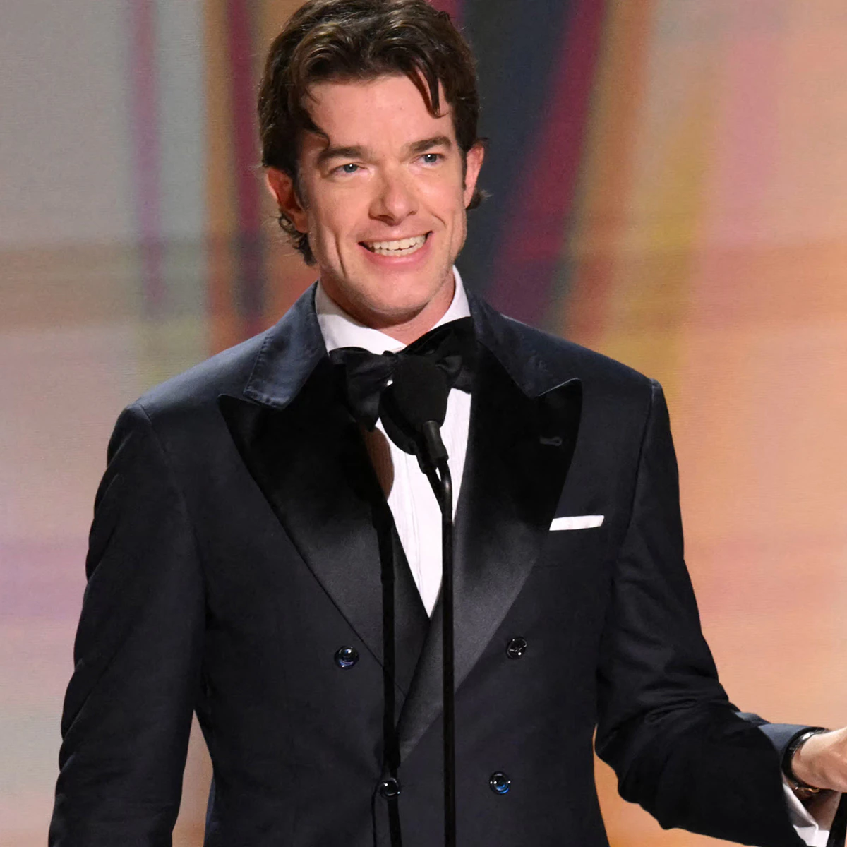 John Mulaney speaking on stage at an awards broadcast