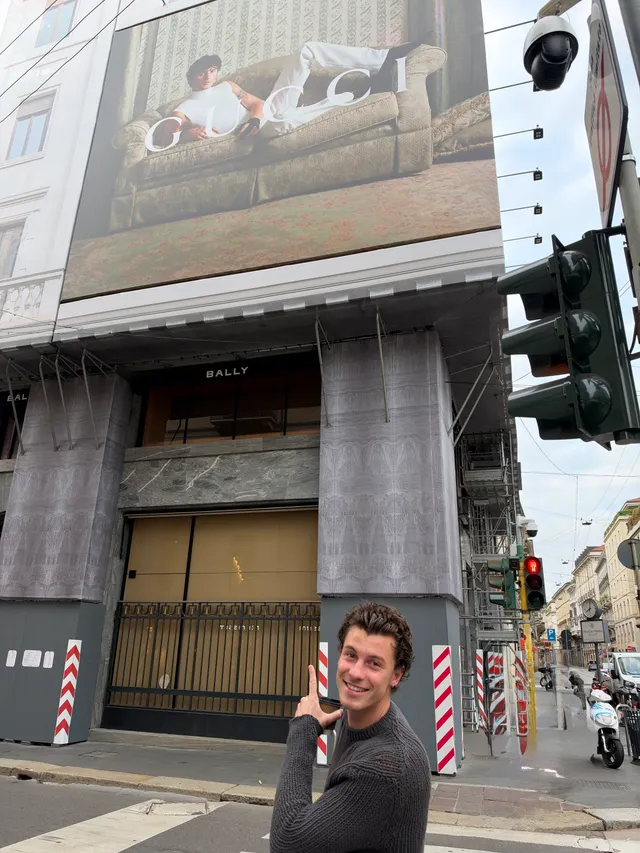 Image may contain Shawn Mendes Advertisement City Urban Road Street Adult Person Light Traffic Light and Baby