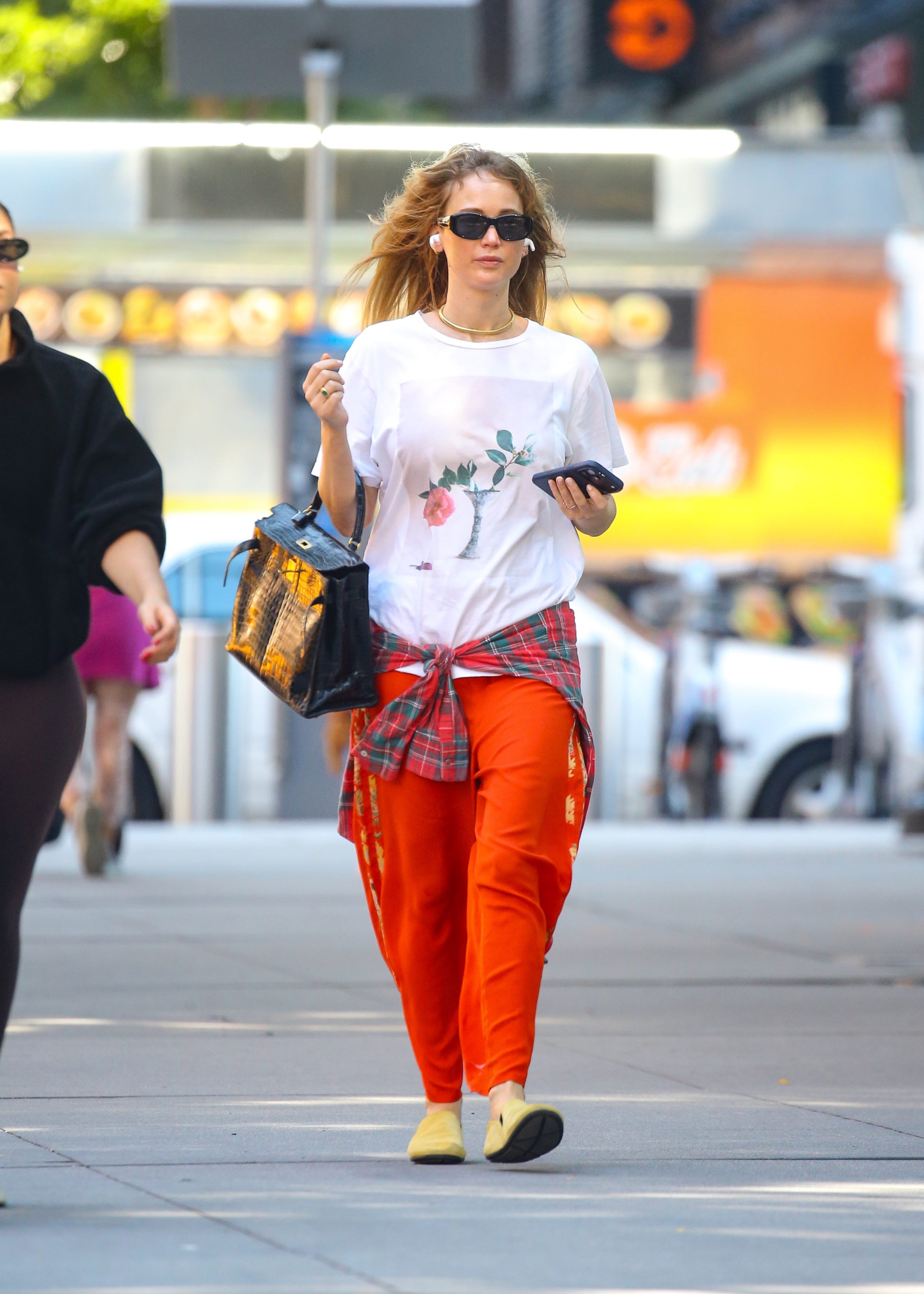 Jennifer Lawrence wearing a relaxed outfit while holding a luxury handbag.