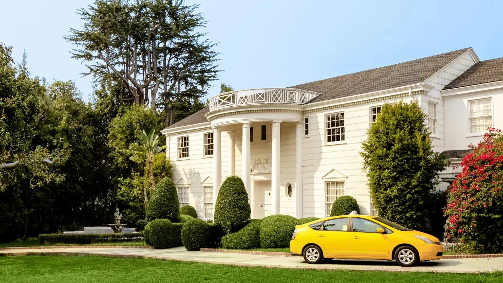 White mansion with yello taxi in driveway