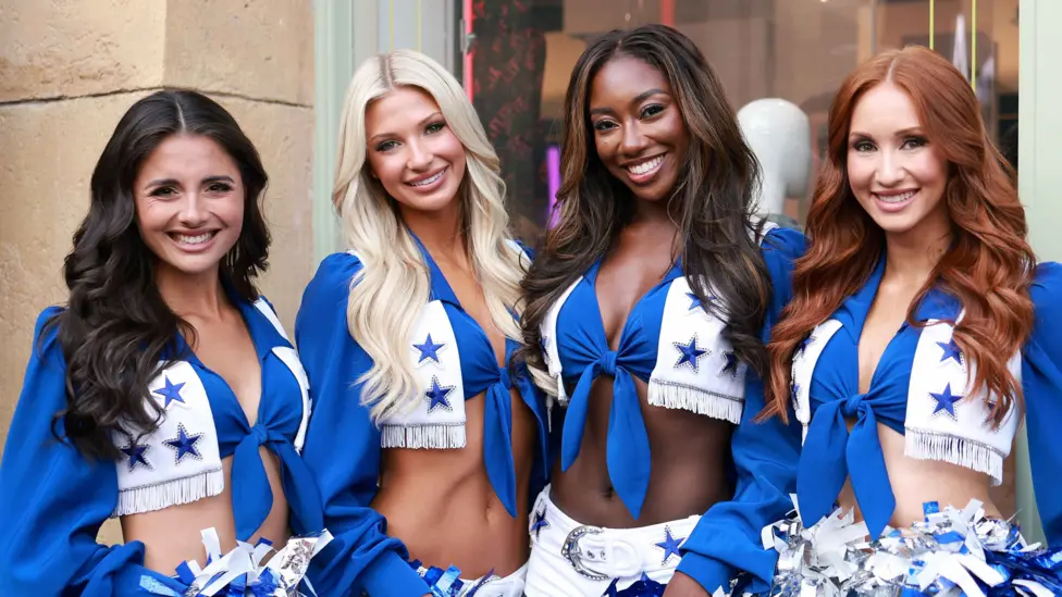 Reece Weaver (far left) with her DCC squad mates. The group of four wear the signature white and blue DCC costume, which consists of a tie-up long sleeved top, white shorts with a bejewelled belt and pom poms.