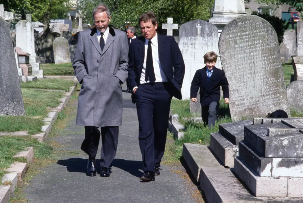 A still image showing John Nettles on the set of Bergerac in a graveyard