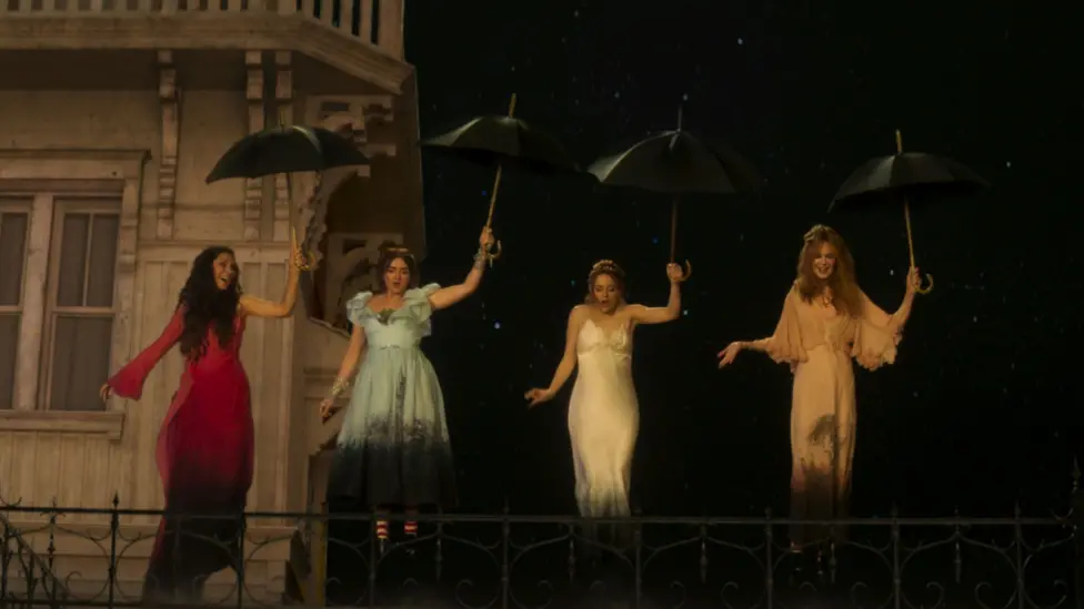 Sandra Bullock, Maisie Williams, Joey King and Nicole Kidman portraying their Practical Magic 2 characters Sally, Antonia, Kylie and Gillian Owens. They are standing on top of a building holding umbrellas in the air and