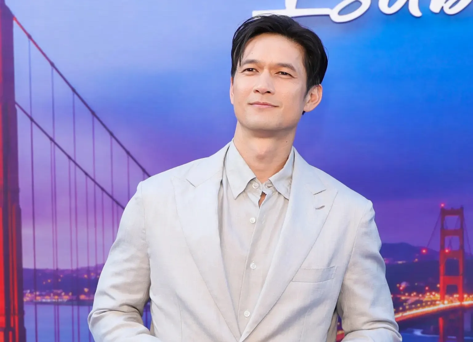 Harry Shum Jr. in a light suit against a Golden Gate Bridge backdrop.