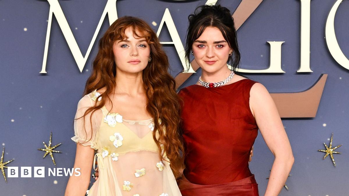 Joey King and Maisie Williams attend the Practical Magic 2 European Premiere in London. Joey wears a cream dress with a lace overlay and flower details and her red hair is worn down in waves. Maisie wears a red dress and