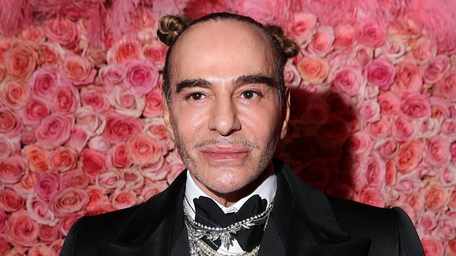Fashion designer John Galliano walking down a runway at a high-fashion runway show.