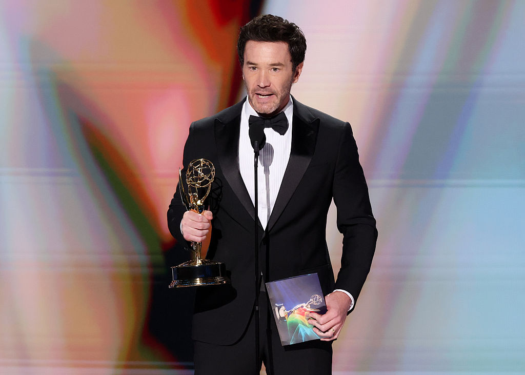 Tom Pelphrey smiling while accepting his trophy on stage at the Emmy Awards