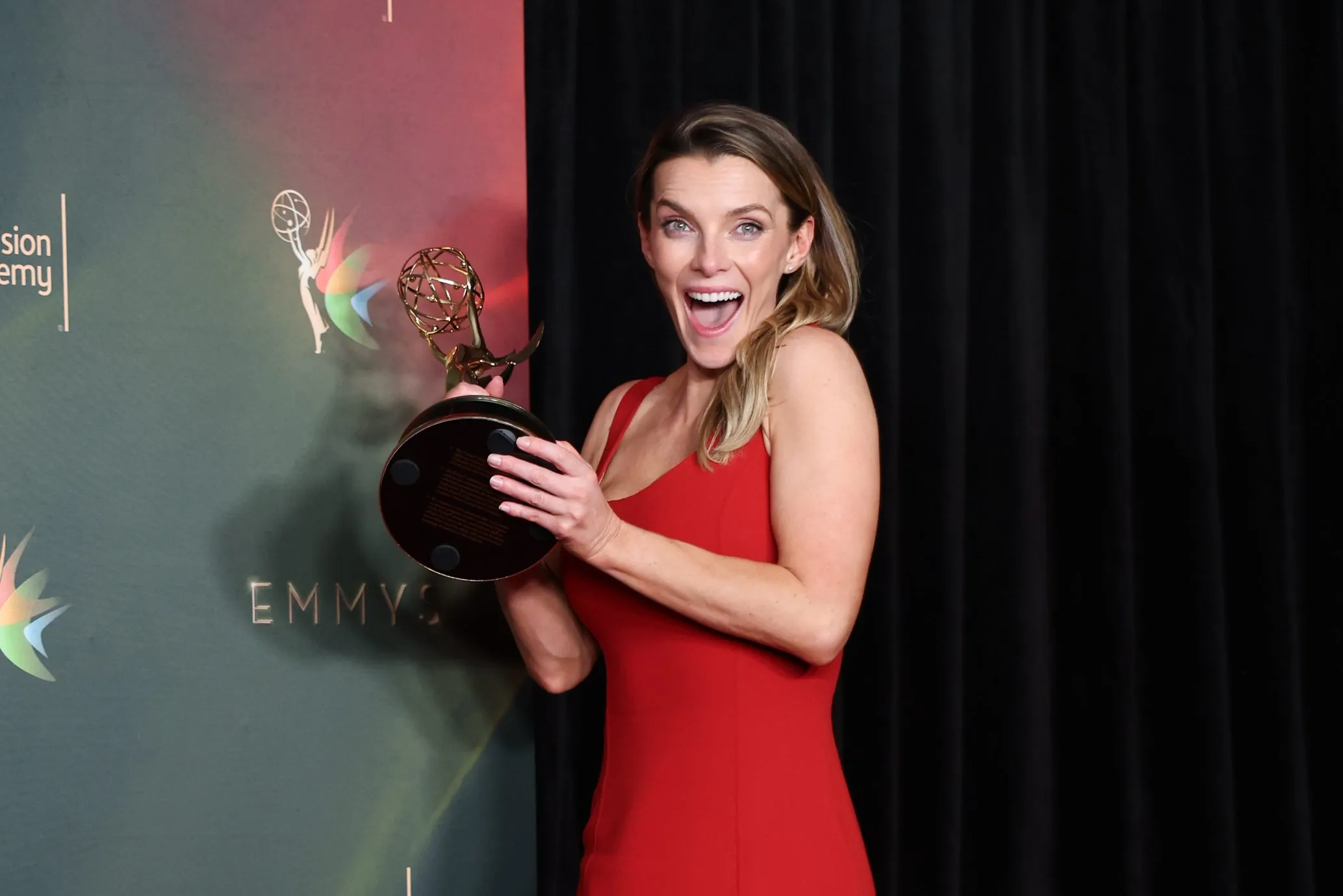 An Emmy Award statuette illuminated on stage during an awards ceremony.