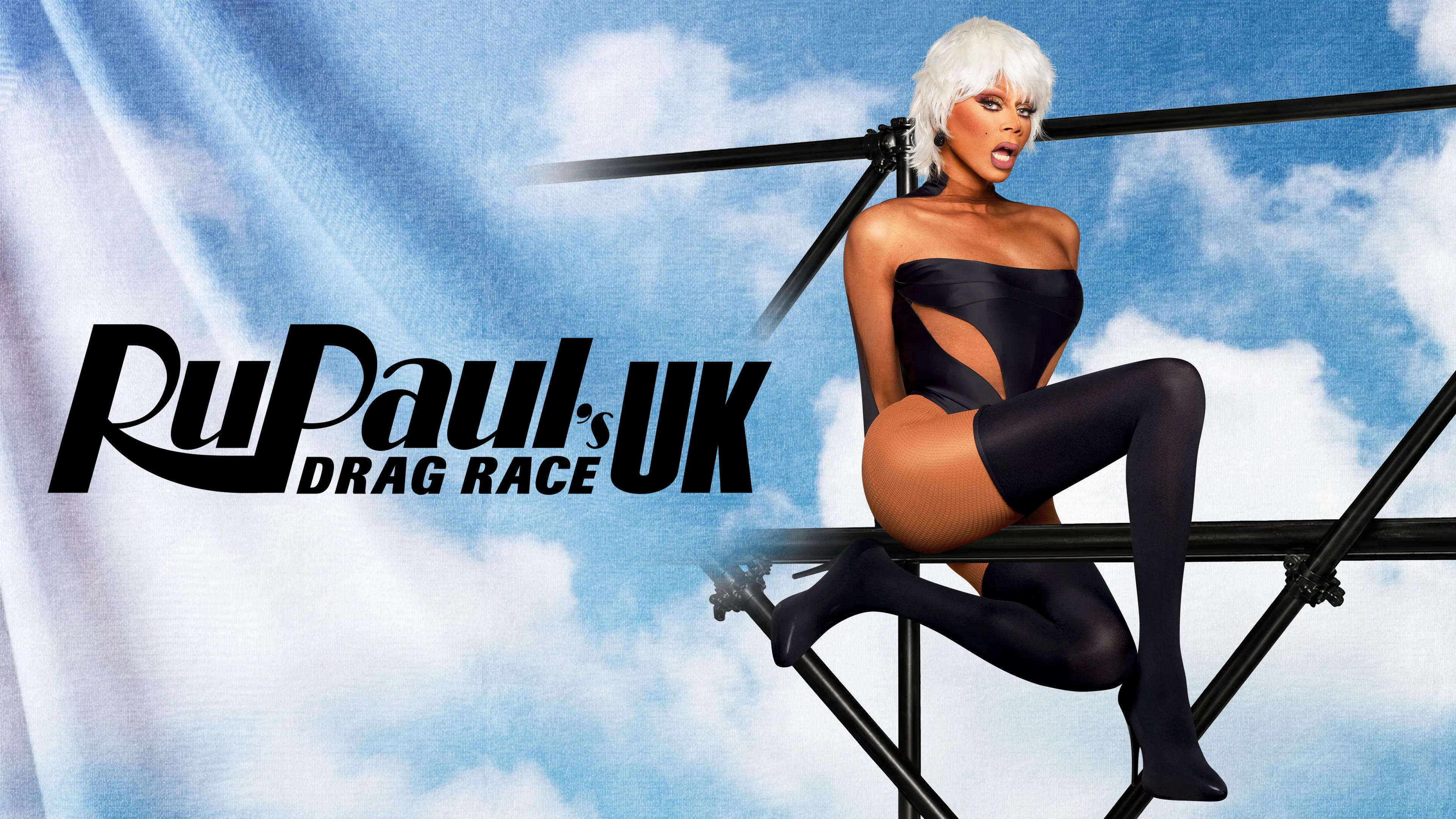 RuPaul posing in a full glamour outfit on stage at a Drag Race event