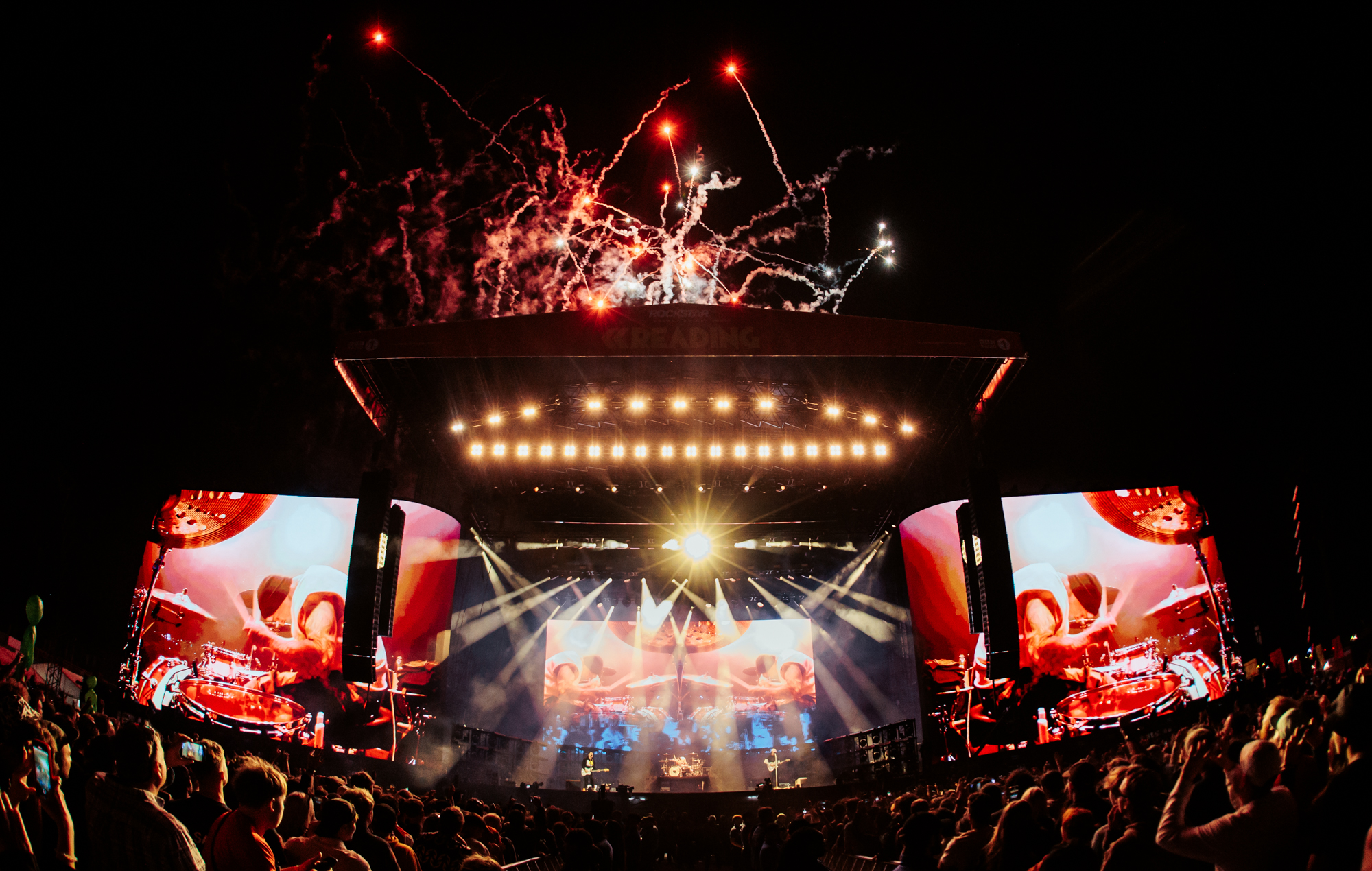 A massive crowd gathered at a festival stage with lights flashing.