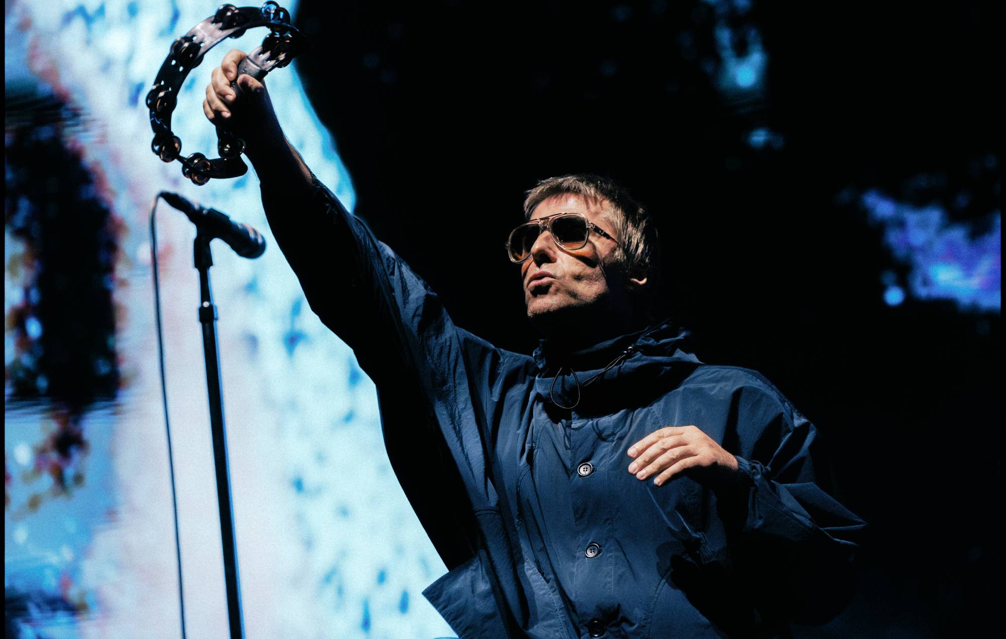 Liam Gallagher performing live on stage with a microphone
