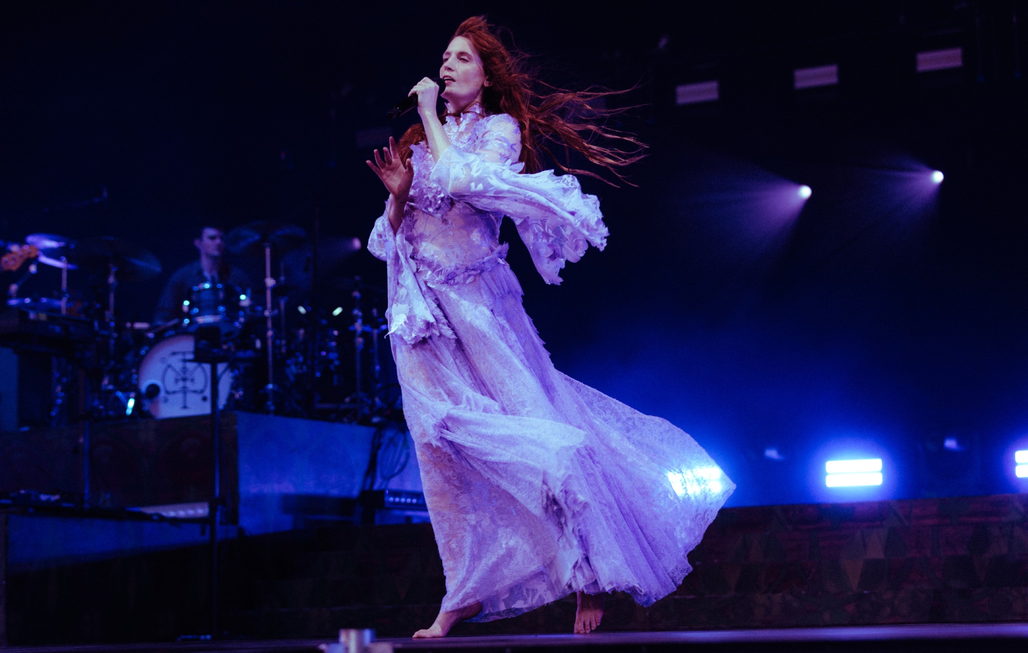 Florence Welch performing on stage with Florence + The Machine at a summer festival