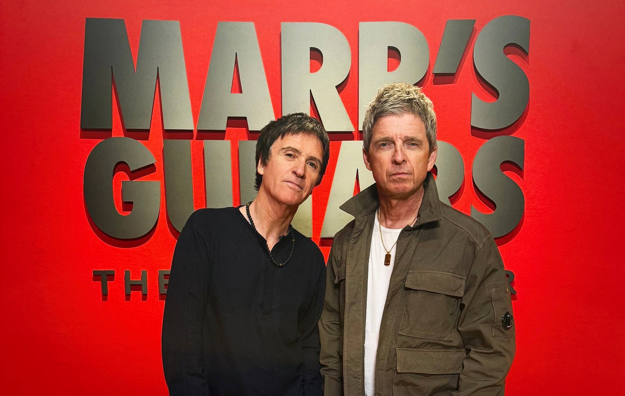 Johnny Marr and Noel Gallagher inspecting guitars at Christie's exhibition in London