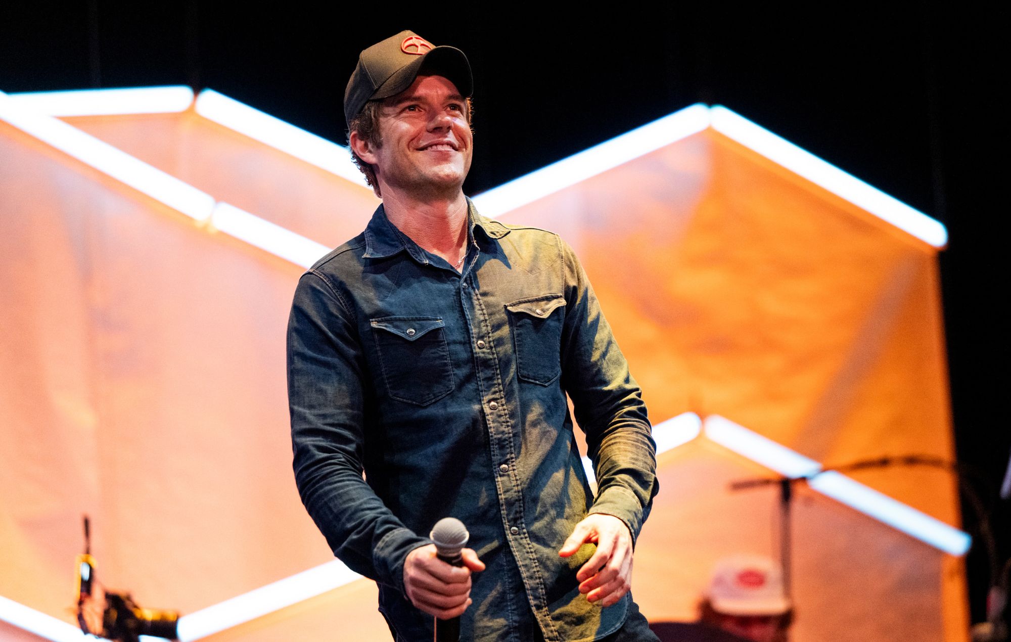Brandon Flowers singing into a microphone during a live concert performance