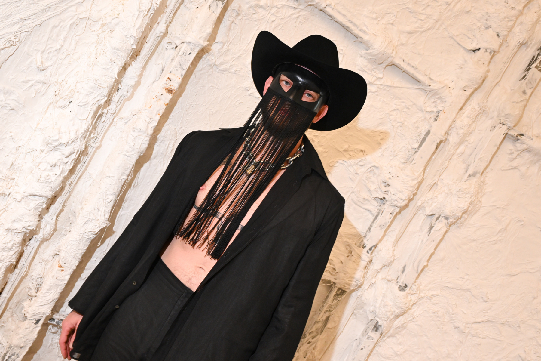 Orville Peck performing on stage in his signature fringe mask