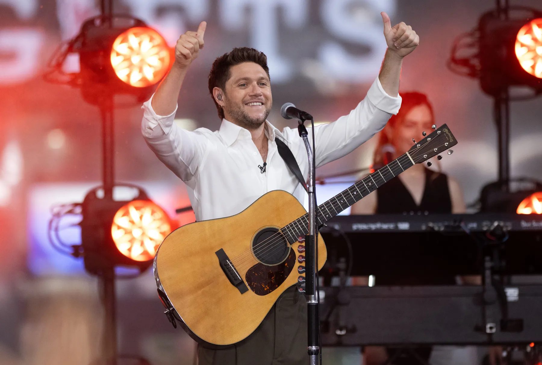 Niall Horan performing live on stage with an acoustic guitar