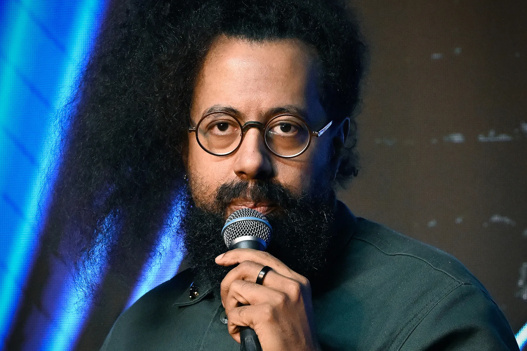 Reggie Watts performing on stage with microphones