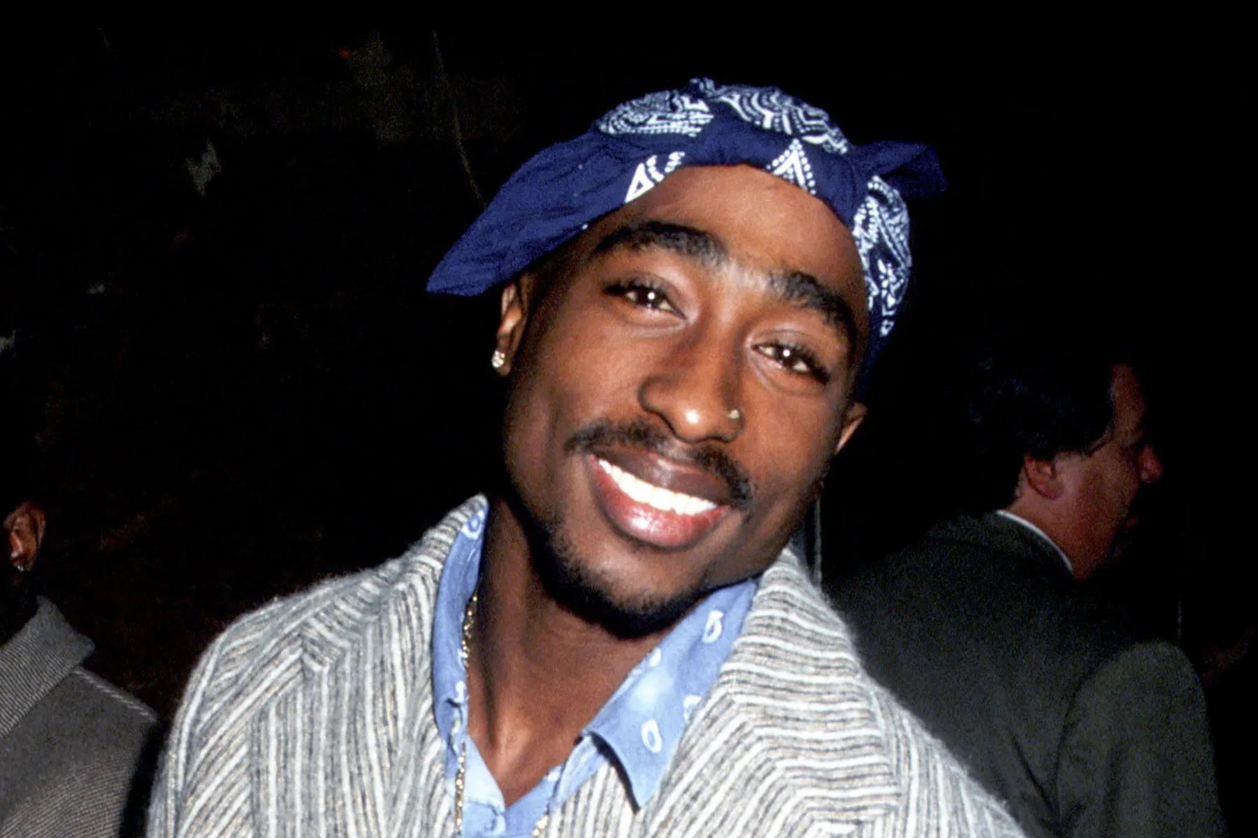 Tupac Shakur smiling at a public event in the 1990s