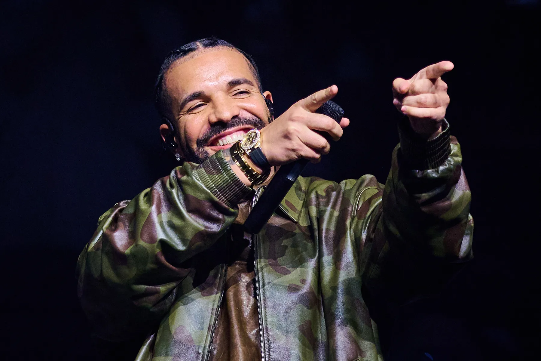 Drake performing on stage under red spot lights during a stadium tour