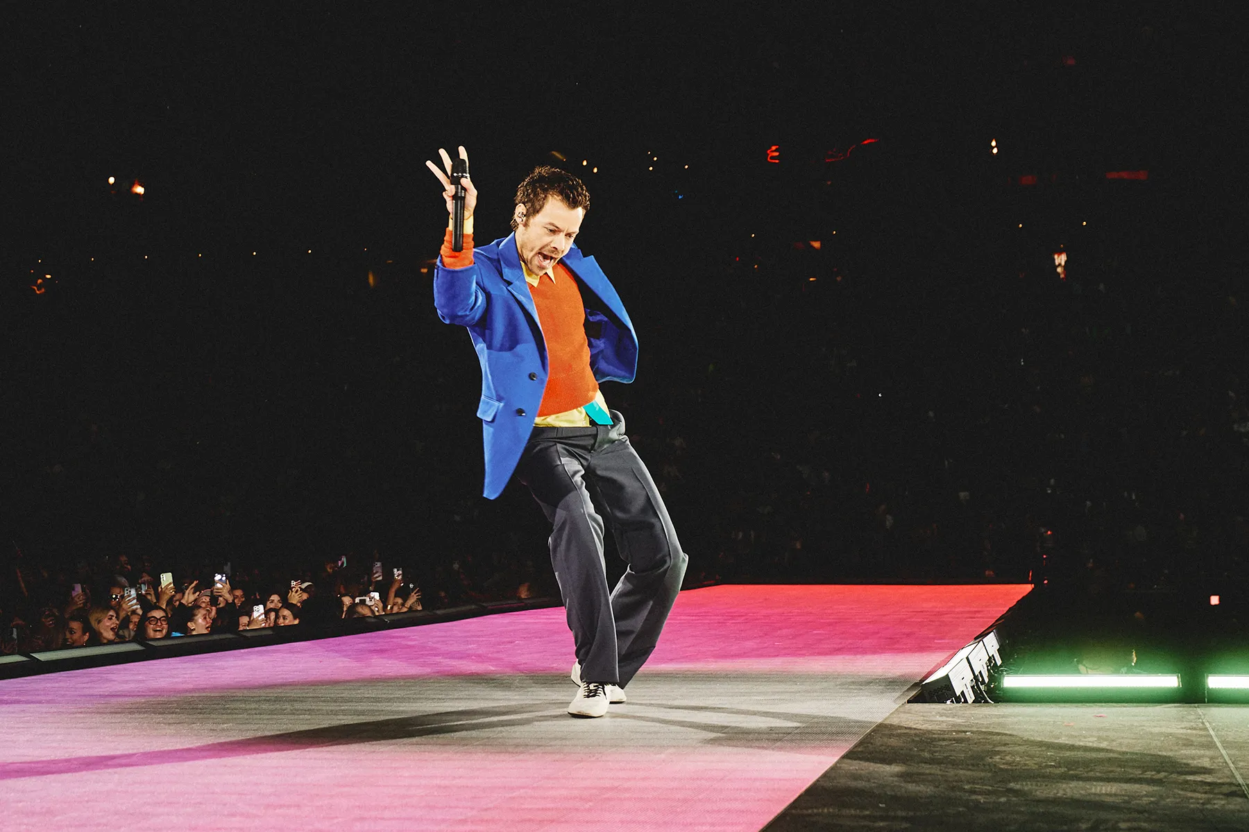 Harry Styles performing live on stage under concert lights.
