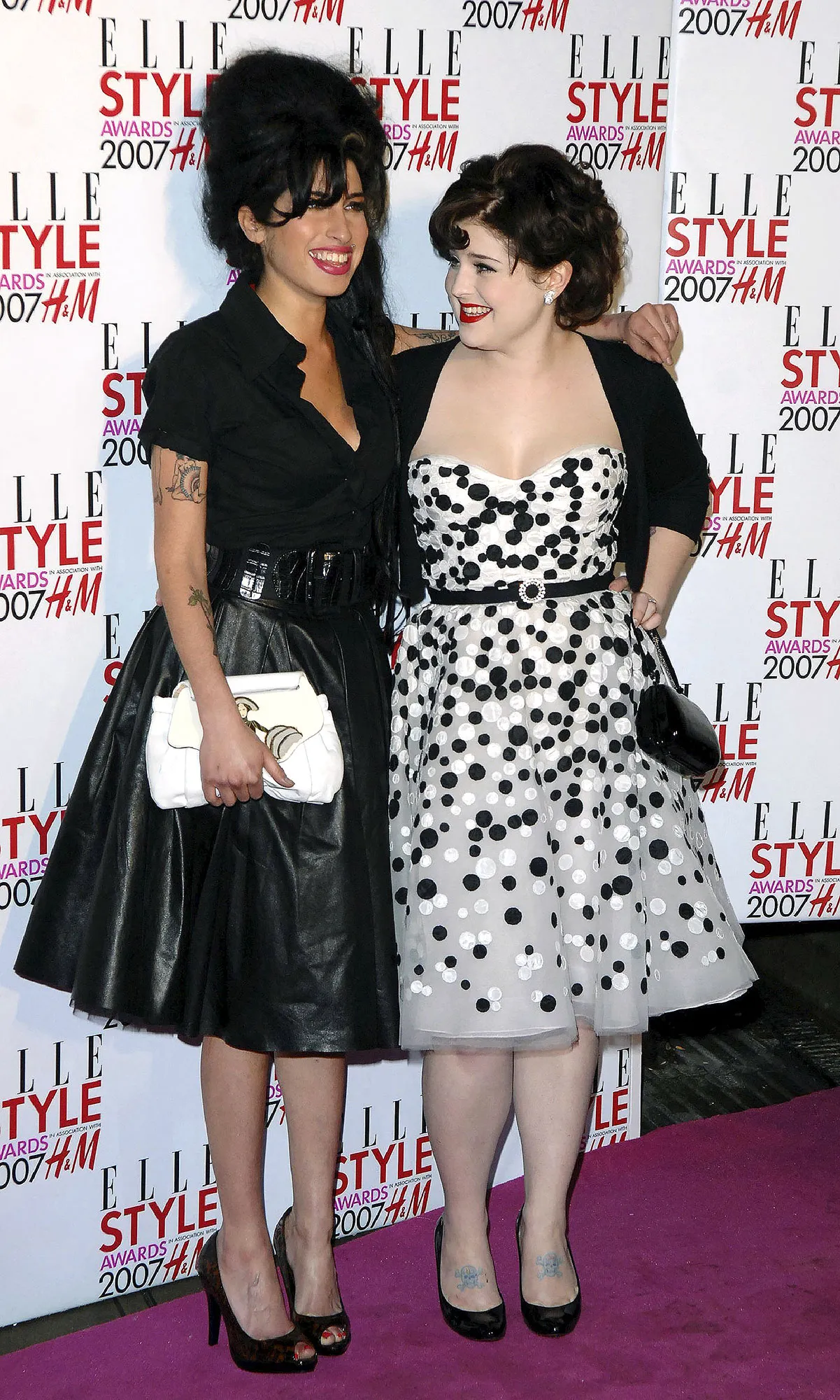 Kelly Osbourne and Amy Winehouse smiling together in a throwback photo