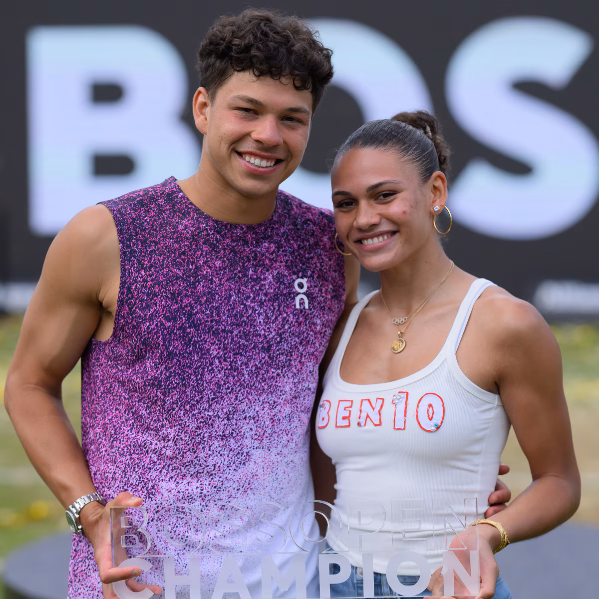 Trinity Rodman and Ben Shelton smiling together at a summer sporting event.
