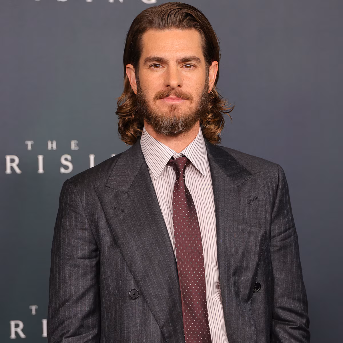 Andrew Garfield attending an event in a dark suit looking thoughtful