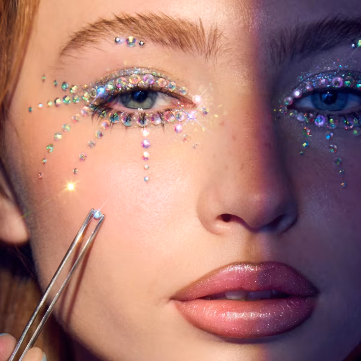 Model with vibrant maximalist makeup and bedazzled face gems at a fashion show