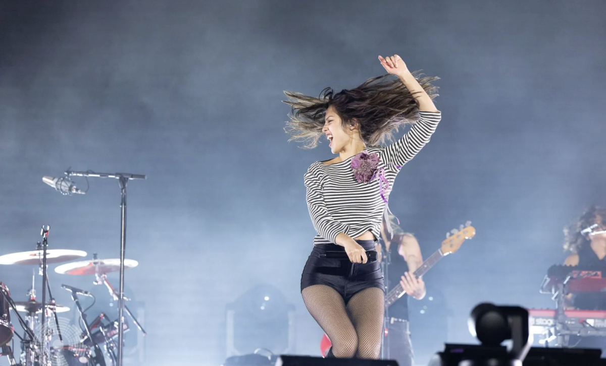 Olivia Rodrigo performing on stage under bright concert lights during her tour.