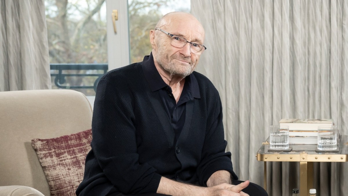Phil Collins performing on stage with a microphone