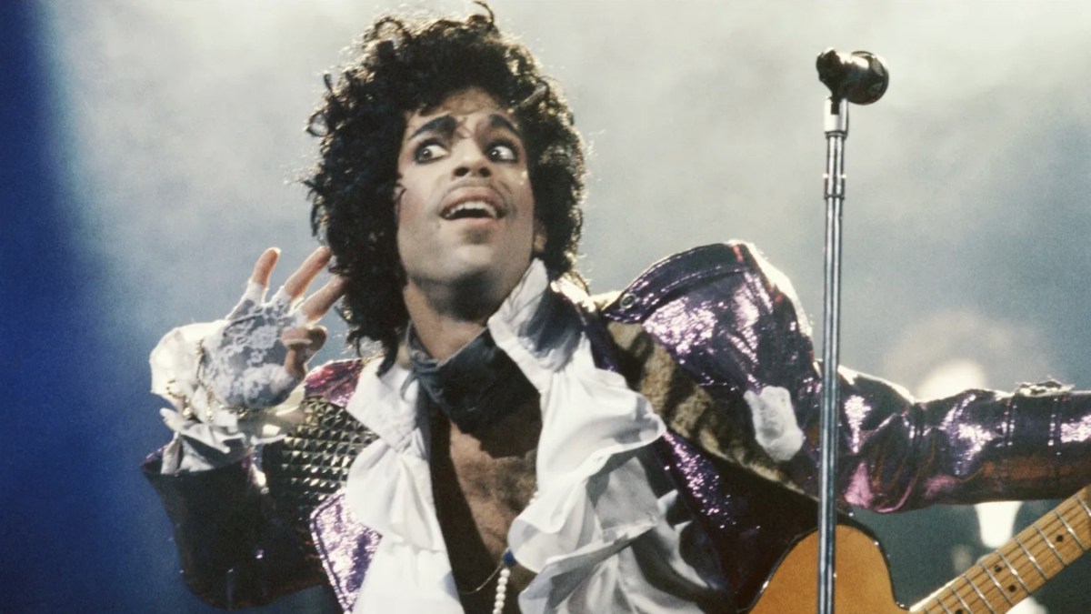 Prince performing live on stage in his signature purple lighting