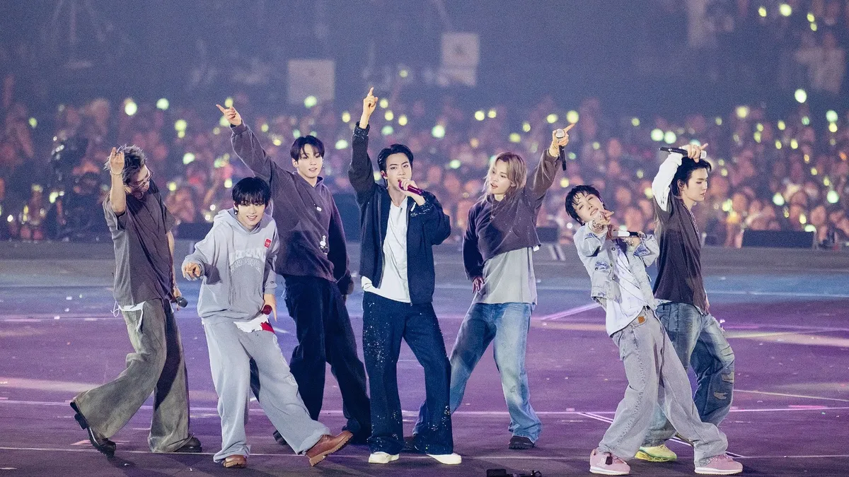 BTS performing live on stage during their ARIRANG world tour concert in front of a stadium crowd.