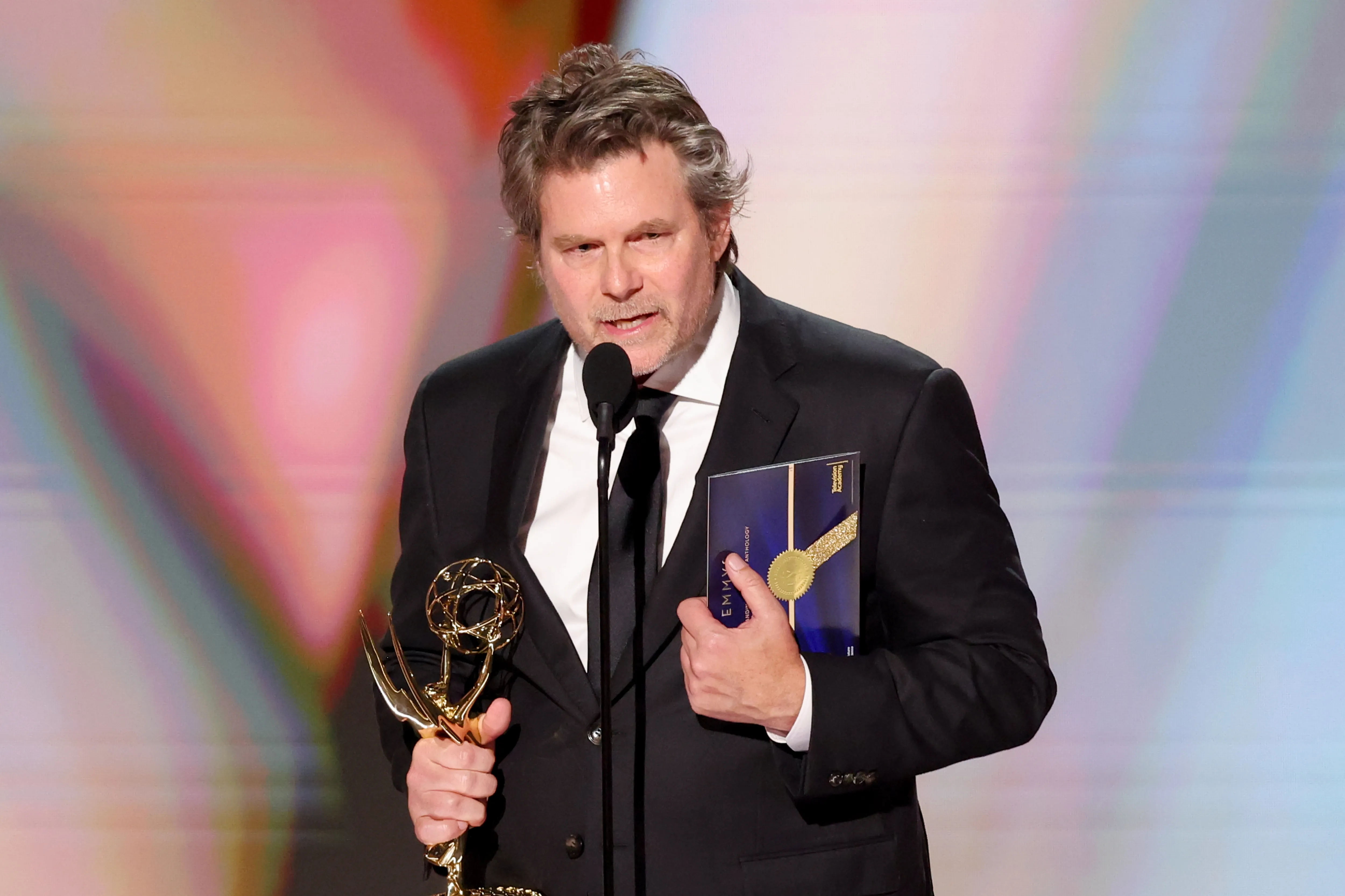 Steve Conrad holding an Emmy award on stage