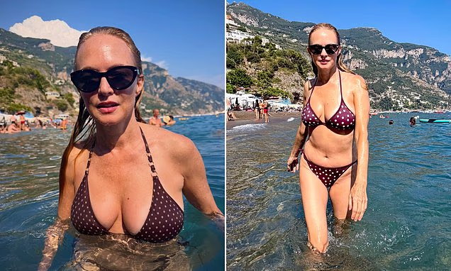 Heather Graham posing in the ocean in Italy wearing a maroon bikini