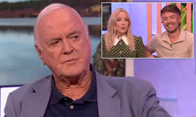 John Cleese sitting on a television chat show sofa during a live interview