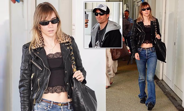 Suki Waterhouse wearing a lace crop top and leopard-print collared leather jacket alongside Robert Pattinson in Venice