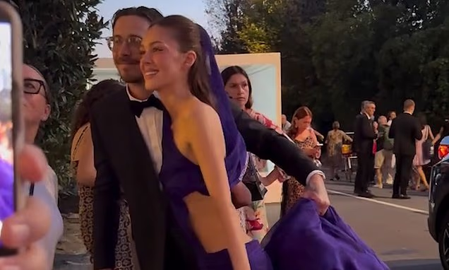 Brooklyn Beckham carrying the train of Nicola Peltz's Balenciaga dress at the Venice Film Festival