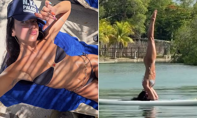 Dua Lipa wearing a strapless bikini while balancing on a paddleboard