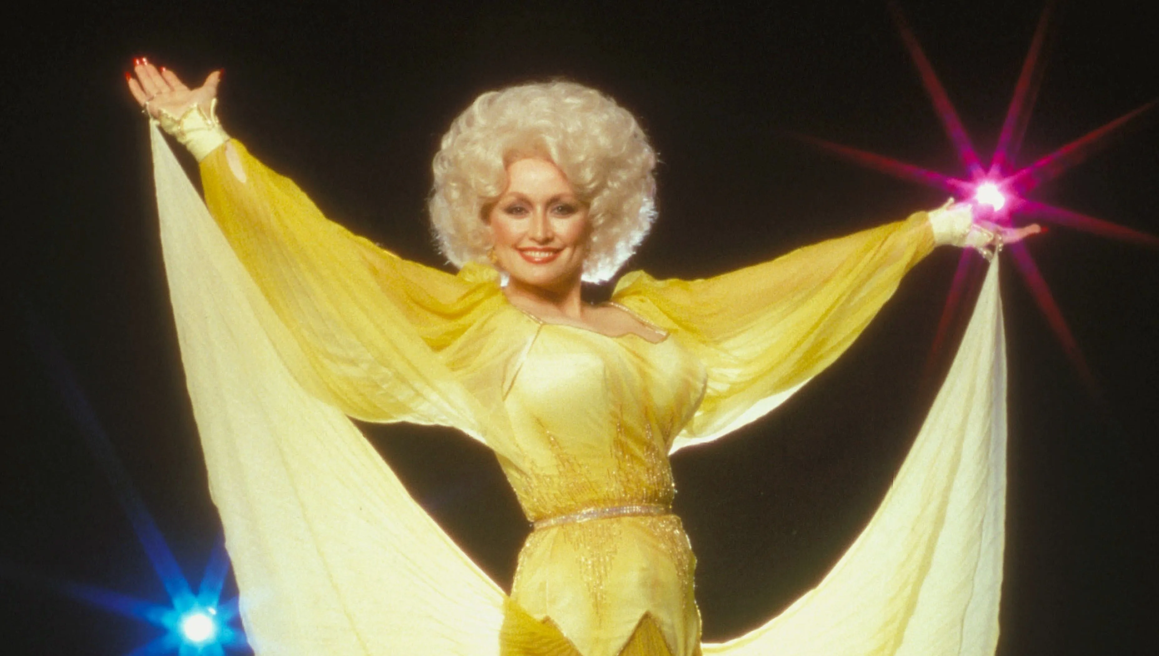 Dolly Parton smiling in a sparkling outfit on stage