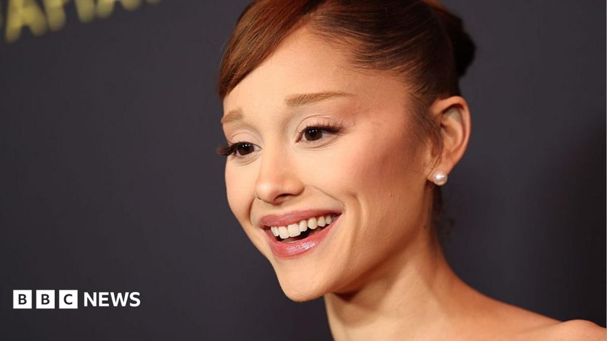 Ariana Grande smiles with hair in bun
