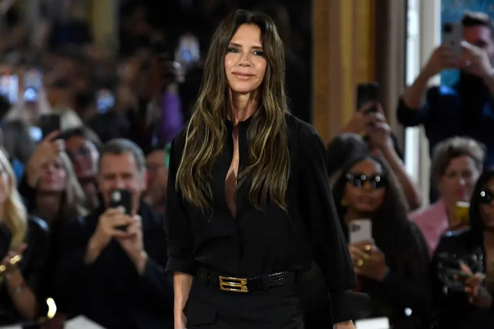 Victoria Beckham standing and smiling in front of a catwalk audience at Victoria Beckham Ready To Wear Spring 2024 on September 29, 2023 in Paris